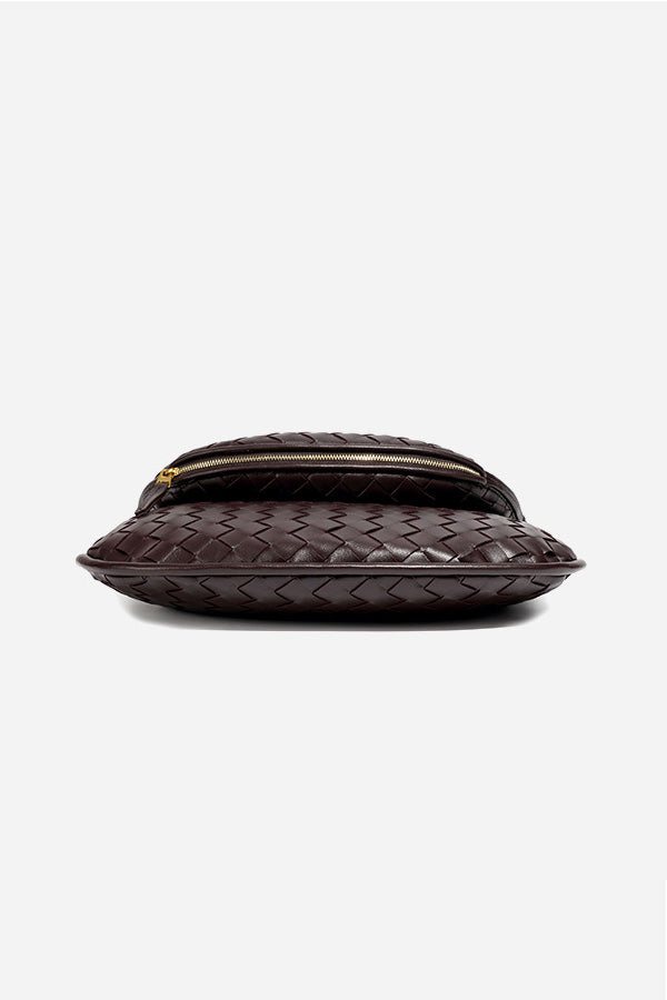 Woman holding dark brown woven leather hobo bag