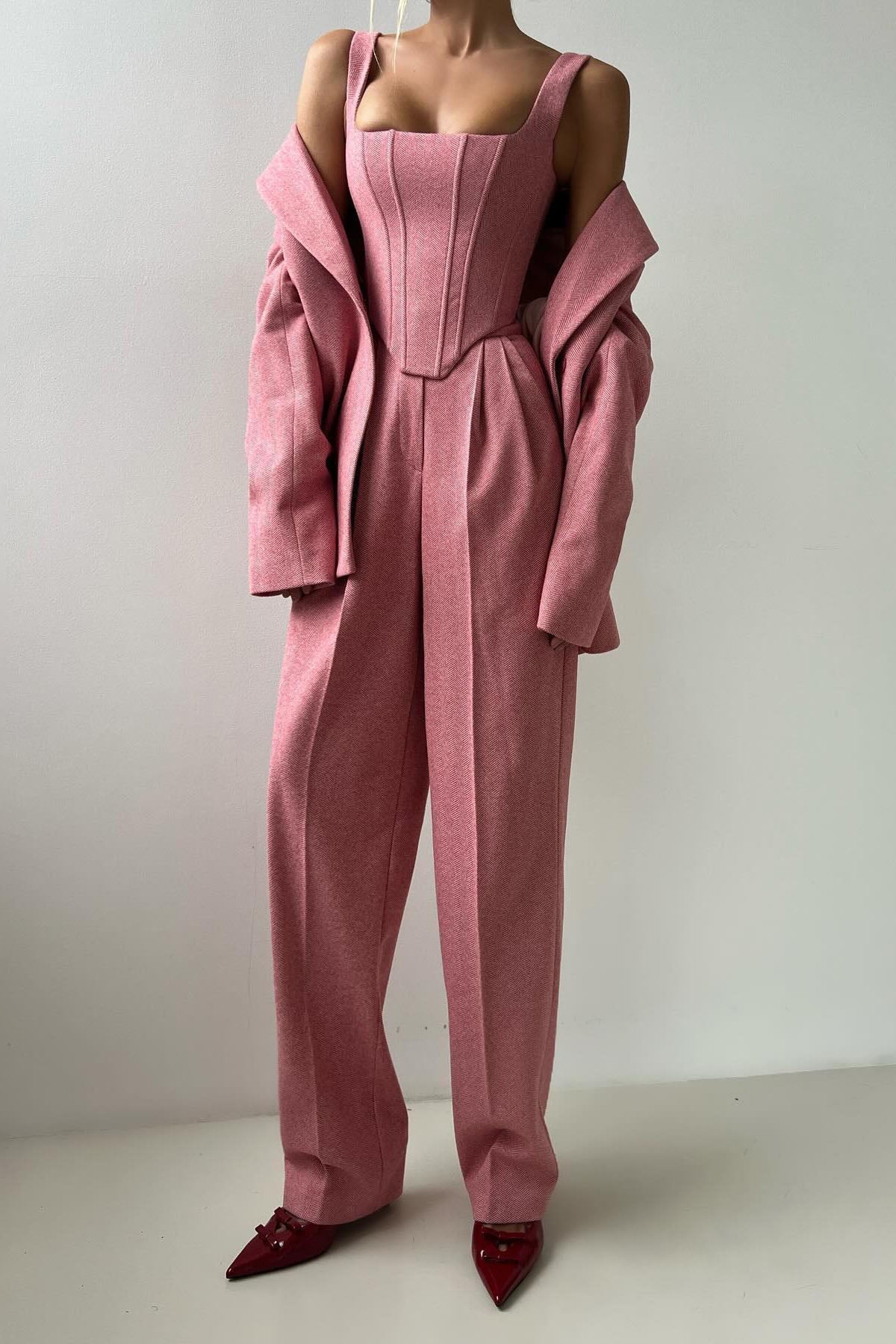 Woman in gray herringbone corset top, wide leg pants, and blazer