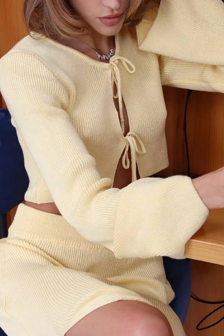 Woman wearing pink ribbed knit cardigan and skirt set with high slit.