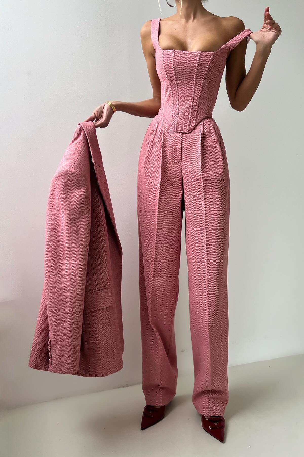 Woman in gray herringbone corset top, wide leg pants, and blazer