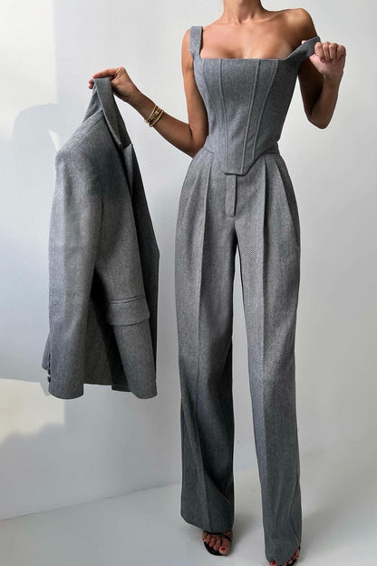 Woman in gray herringbone corset top, wide leg pants, and blazer