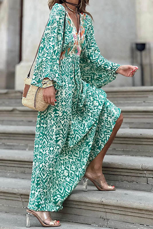Woman in green and white patterned maxi dress climbing stairs