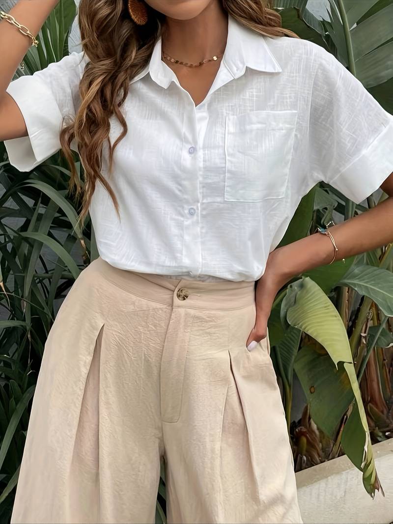 Woman wearing white linen short-sleeve shirt and beige pleated trousers