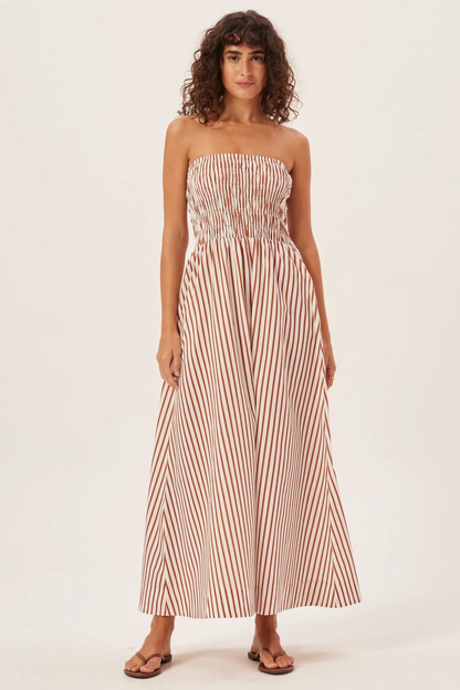 Woman in green and white striped strapless maxi dress holding straw tote bag