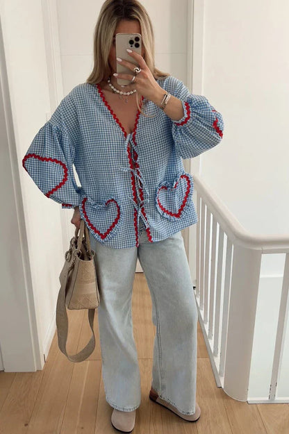 Woman in pink gingham blouse with heart pockets and denim shorts