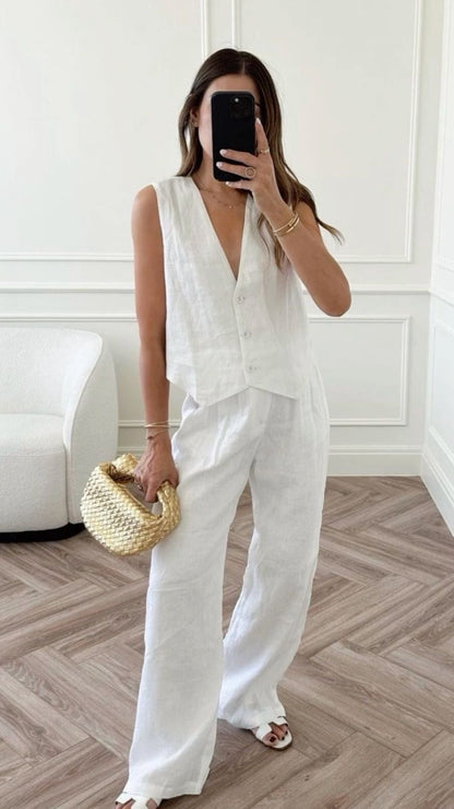 Woman in white linen vest and wide-leg pants on stone steps.