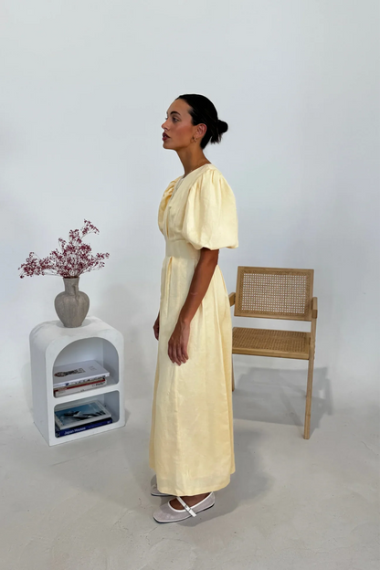 Woman in pale yellow linen maxi dress with puff sleeves