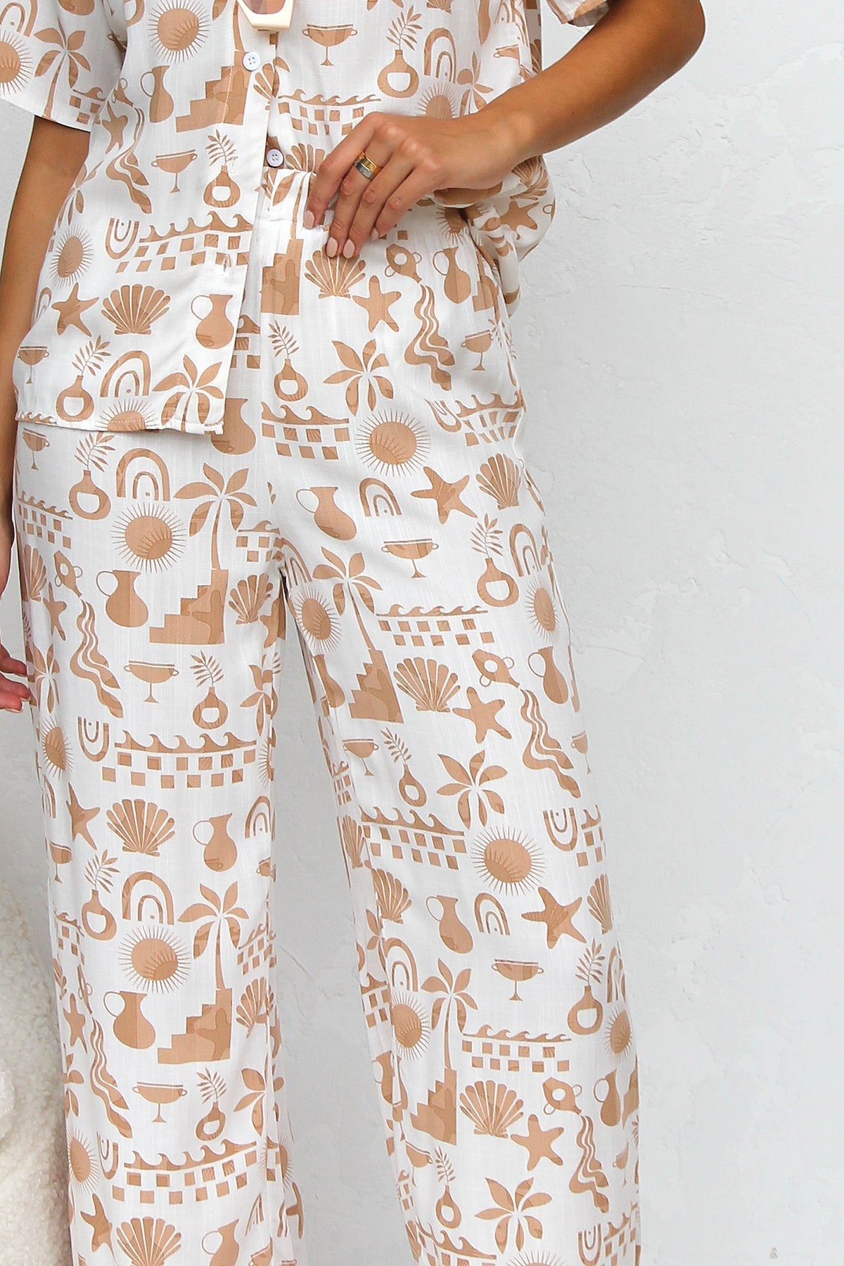 Woman wearing beige linen pajama set with beach-themed print