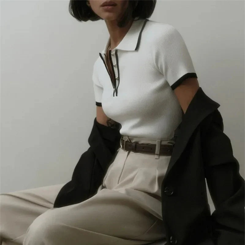 Woman wearing white ribbed knit polo shirt with brown belt and beige trousers