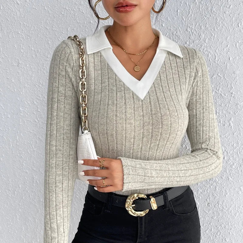Woman wearing a light gray ribbed knit bodysuit with a white collar and black jeans.