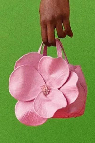 Woman in pink floral chiffon dress holding a red flower-shaped purse