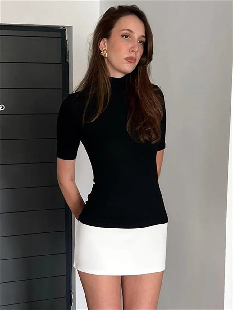 Woman in black ribbed turtleneck and white mini skirt