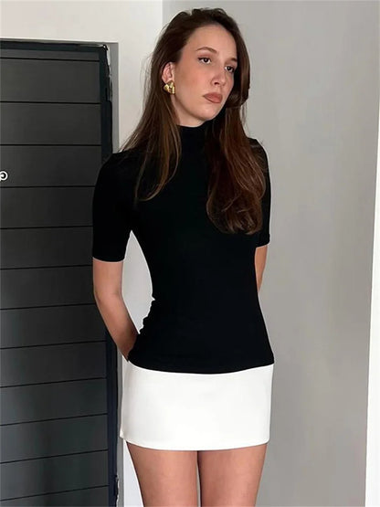 Woman in black ribbed turtleneck and white mini skirt
