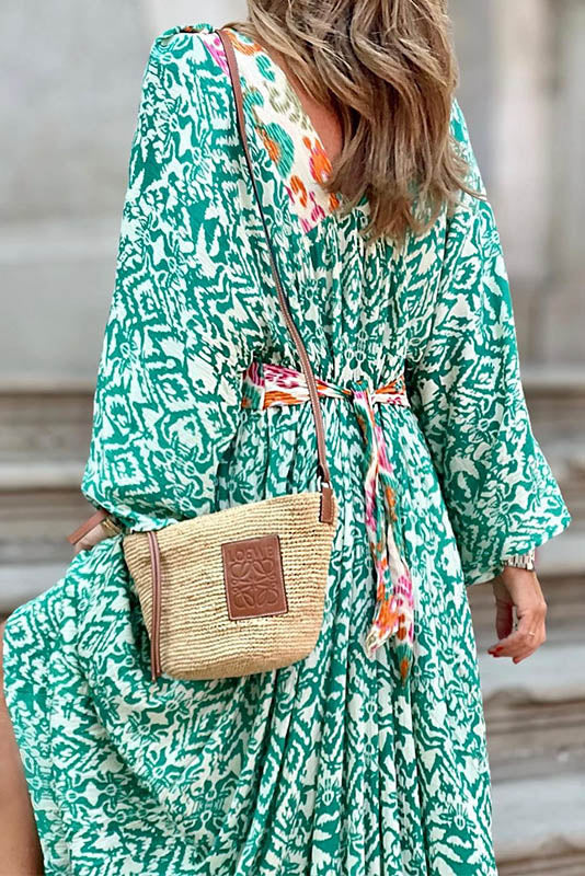Woman in green and white patterned maxi dress climbing stairs