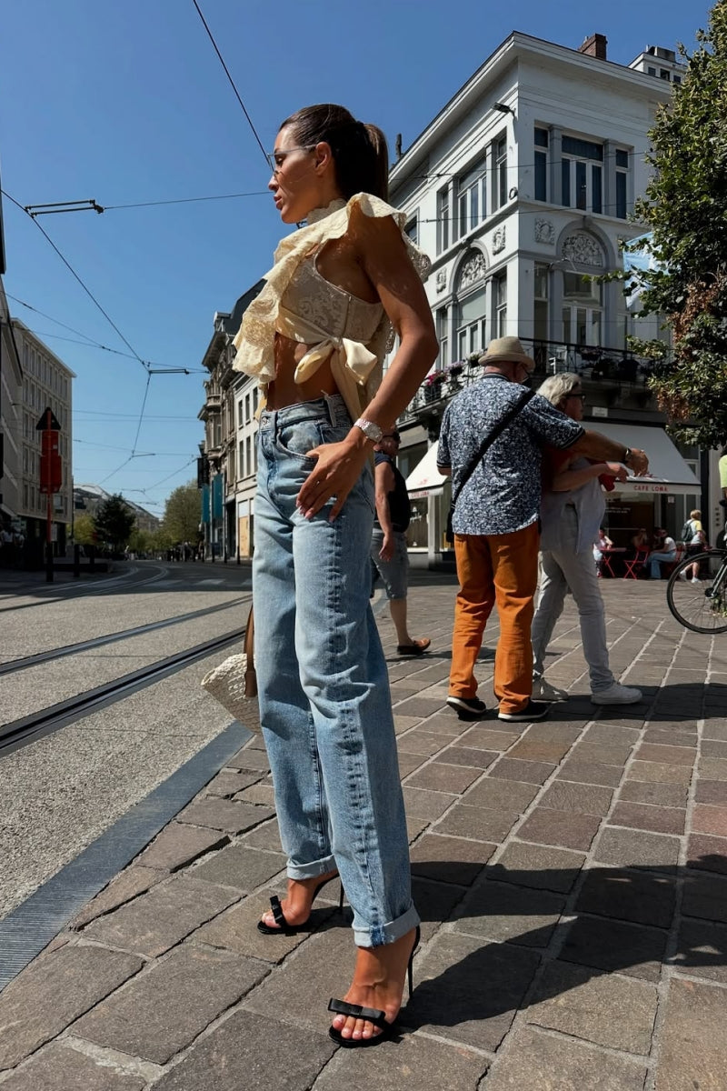 Woman in cream lace crop top and jeans on city street