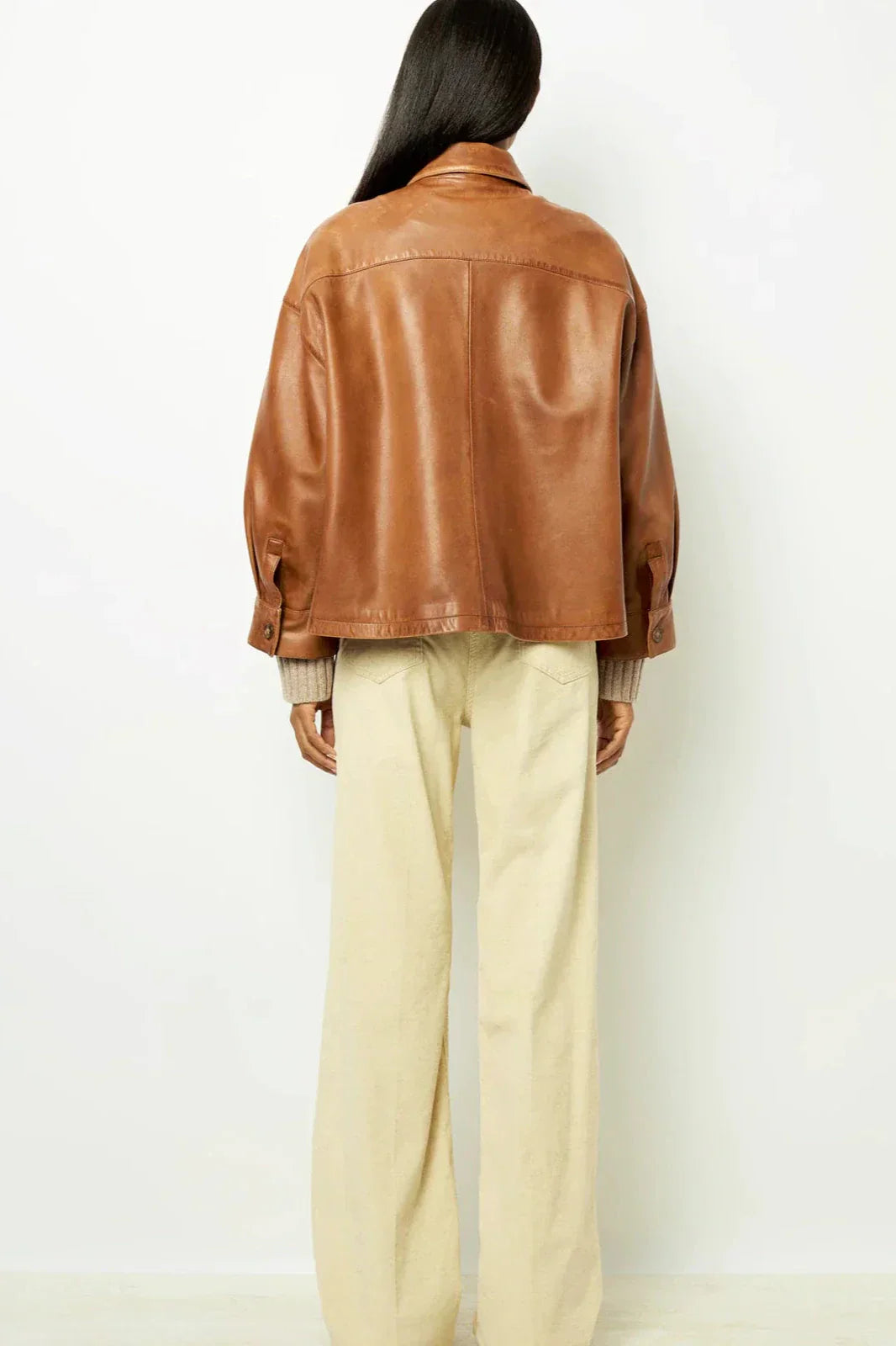 Woman wearing tan leather jacket and patterned sweater