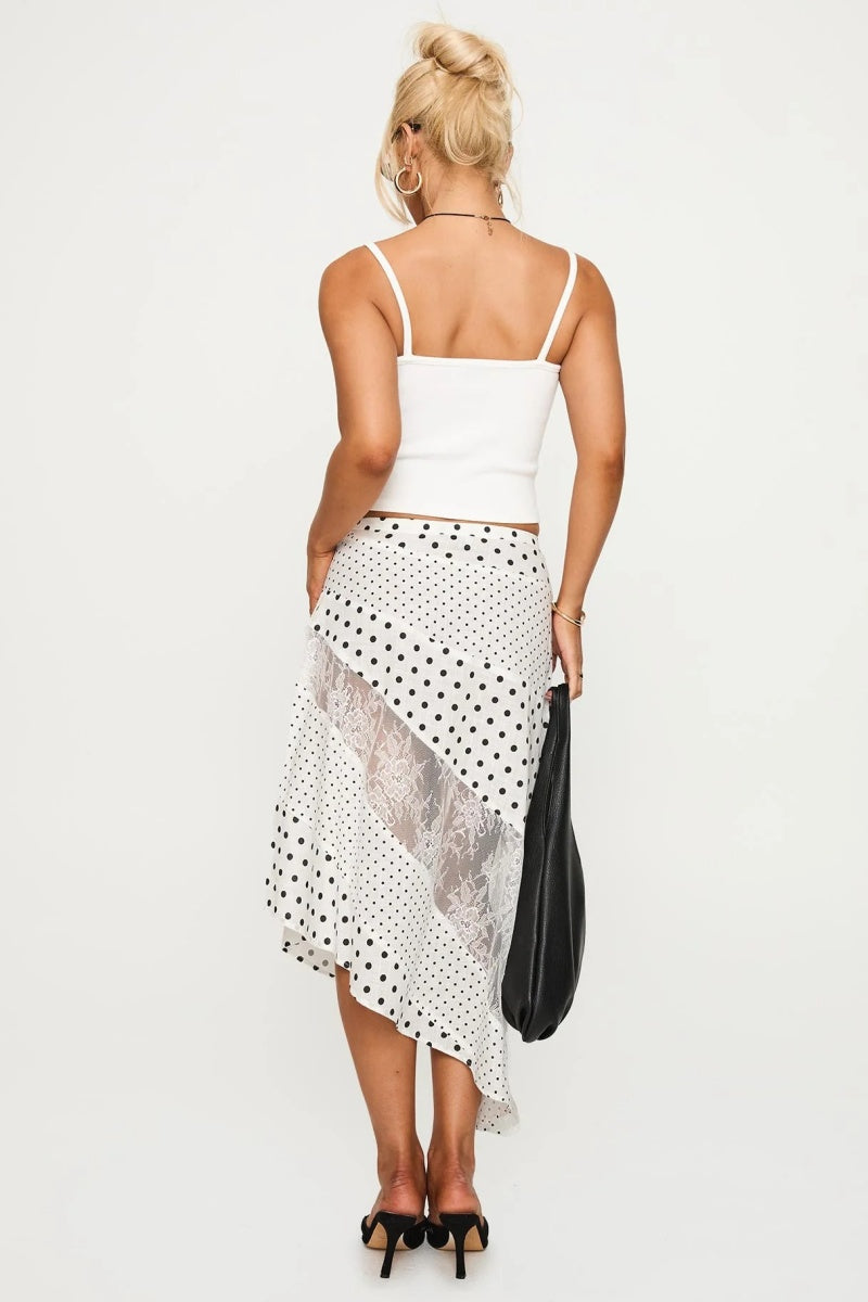 Woman in white tank top and polka dot and lace asymmetrical skirt