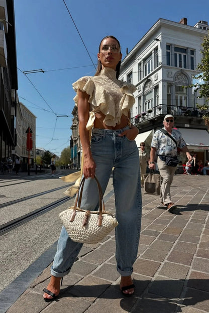 Woman in cream lace crop top and jeans on city street
