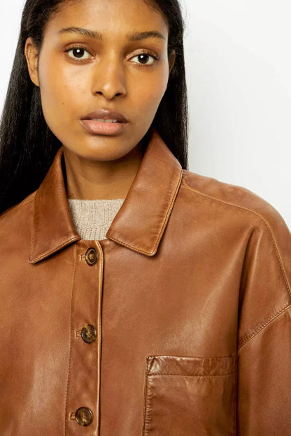 Woman wearing tan leather jacket and patterned sweater