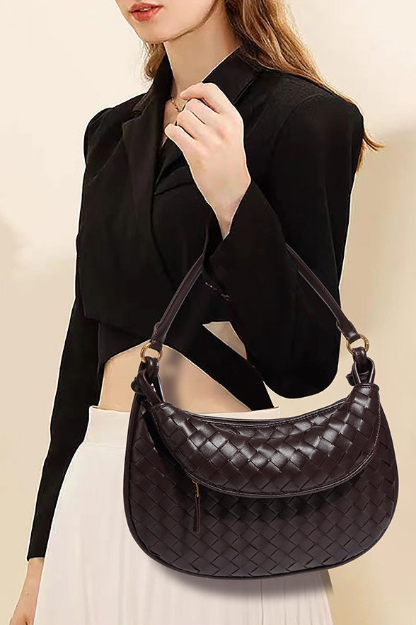 Close-up of a woman holding a dark brown woven hobo bag with gold hardware.