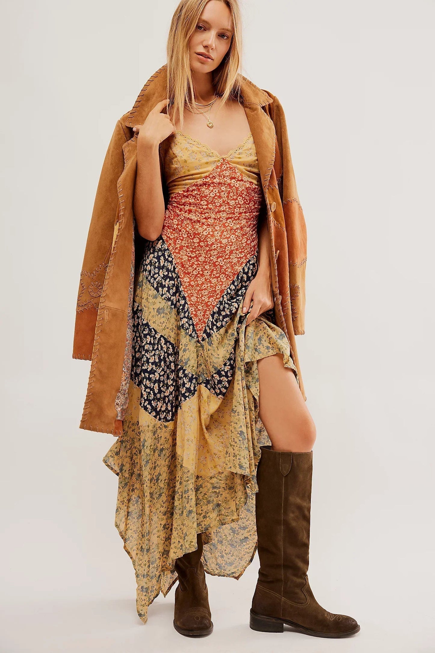 Woman wearing floral patchwork dress, suede jacket, and knee-high boots