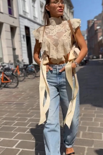 Woman in cream lace crop top and jeans on city street