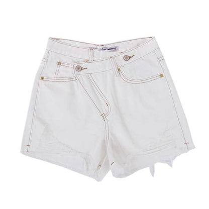 Woman wearing light wash denim shorts with asymmetrical waist and distressed hem.