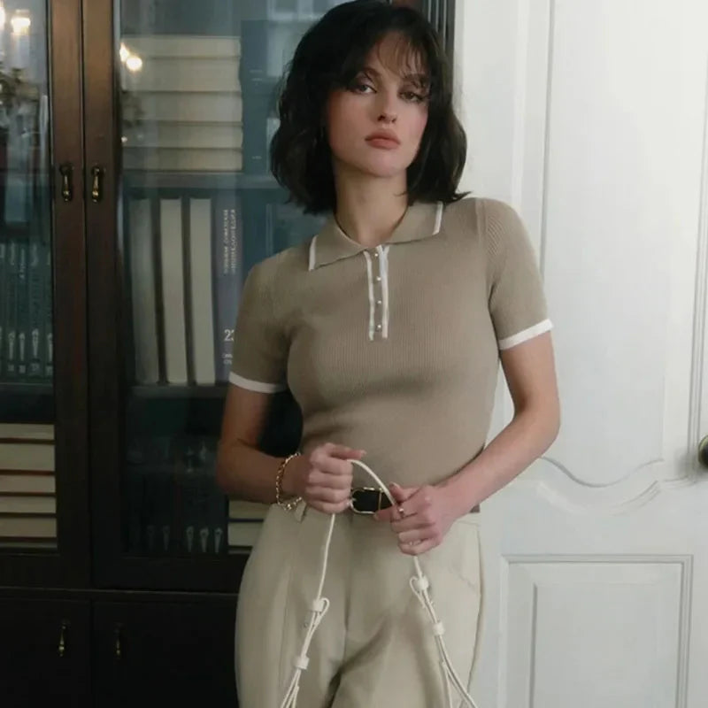 Woman wearing white ribbed knit polo shirt with brown belt and beige trousers