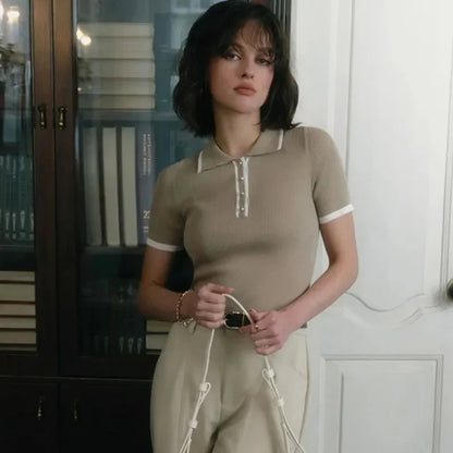 Woman wearing white ribbed knit polo shirt with brown belt and beige trousers