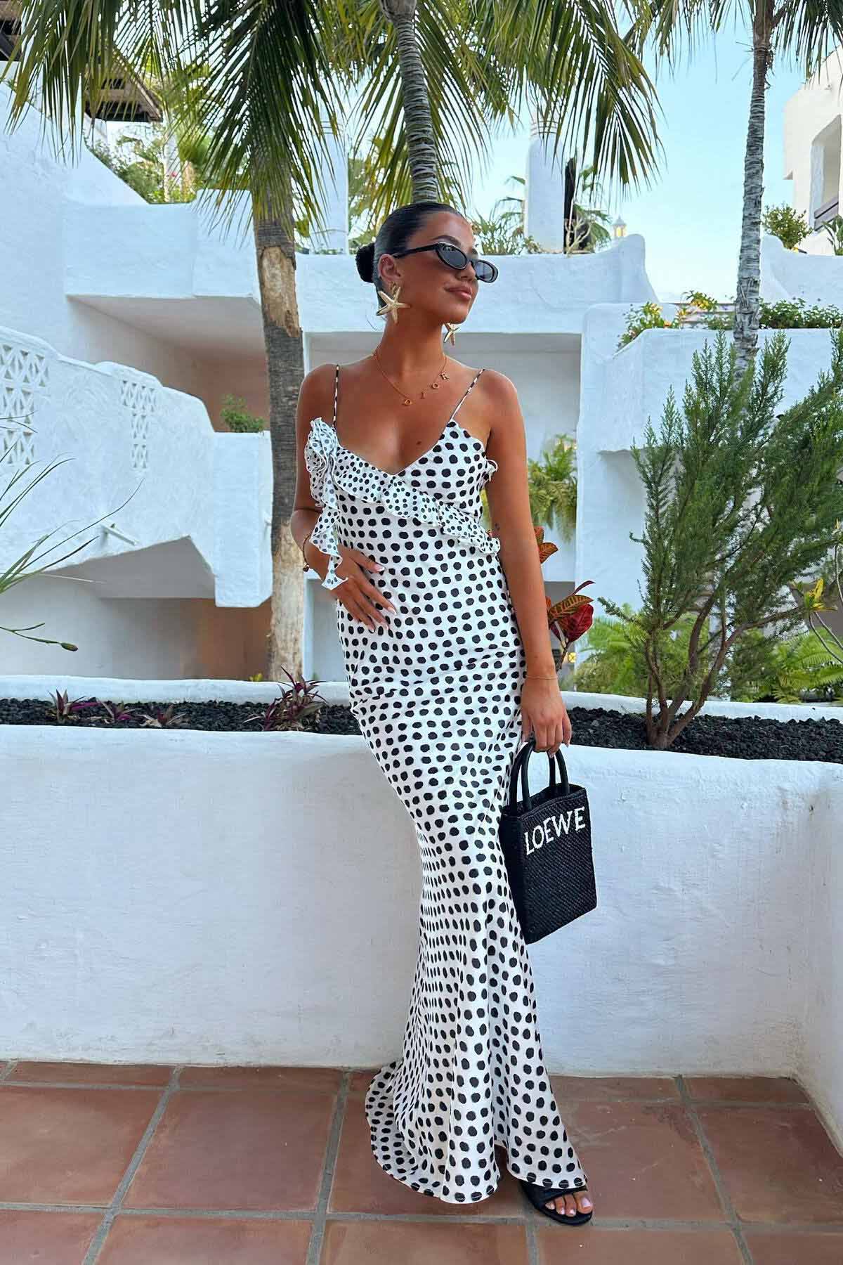Woman in white satin polka dot dress with ruffle detail