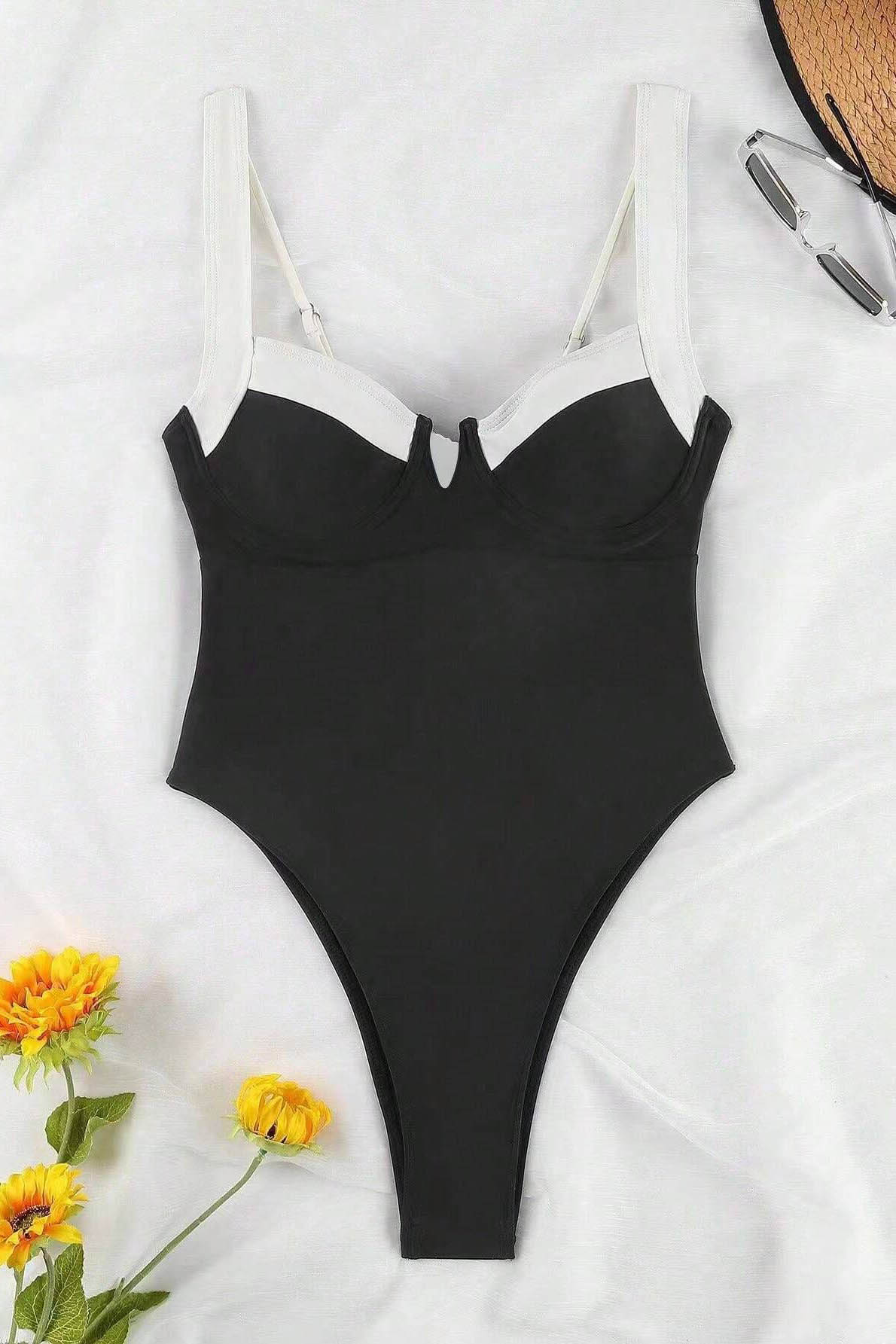 Woman in black and white one-piece swimsuit by the ocean