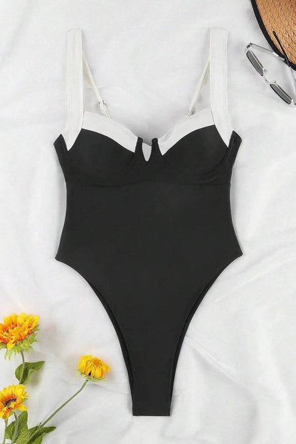 Woman in black and white one-piece swimsuit by the ocean