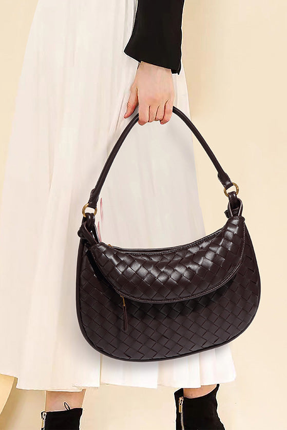 Woman holding dark brown woven leather hobo bag