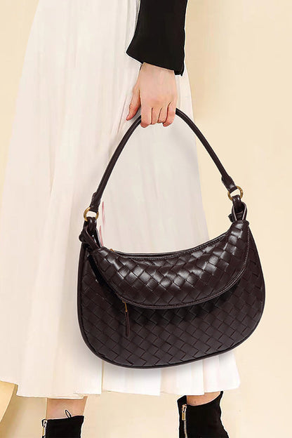 Woman holding dark brown woven leather hobo bag