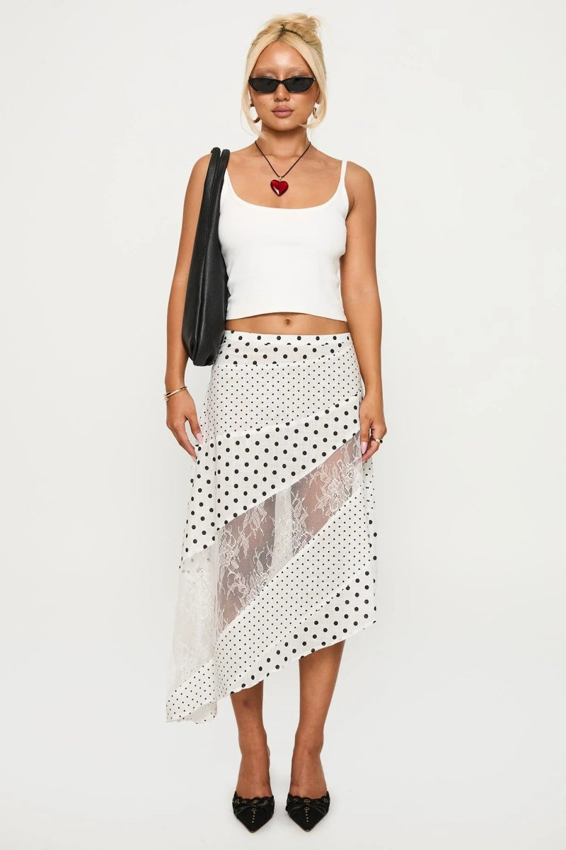 Woman in white tank top and polka dot and lace asymmetrical skirt