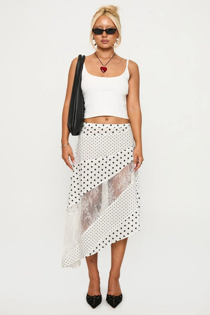 Woman in white tank top and polka dot and lace asymmetrical skirt