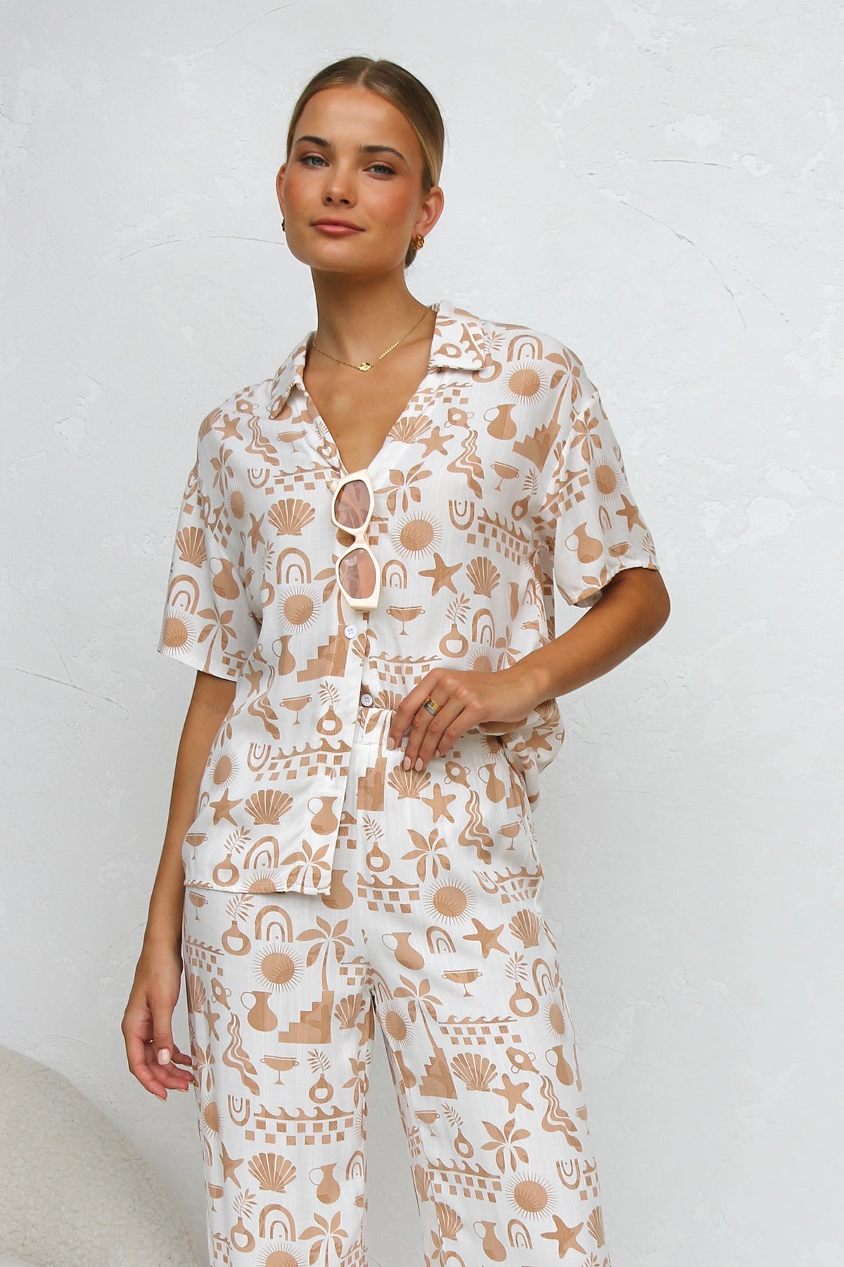 Woman wearing beige linen pajama set with beach-themed print