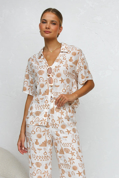 Woman wearing beige linen pajama set with beach-themed print