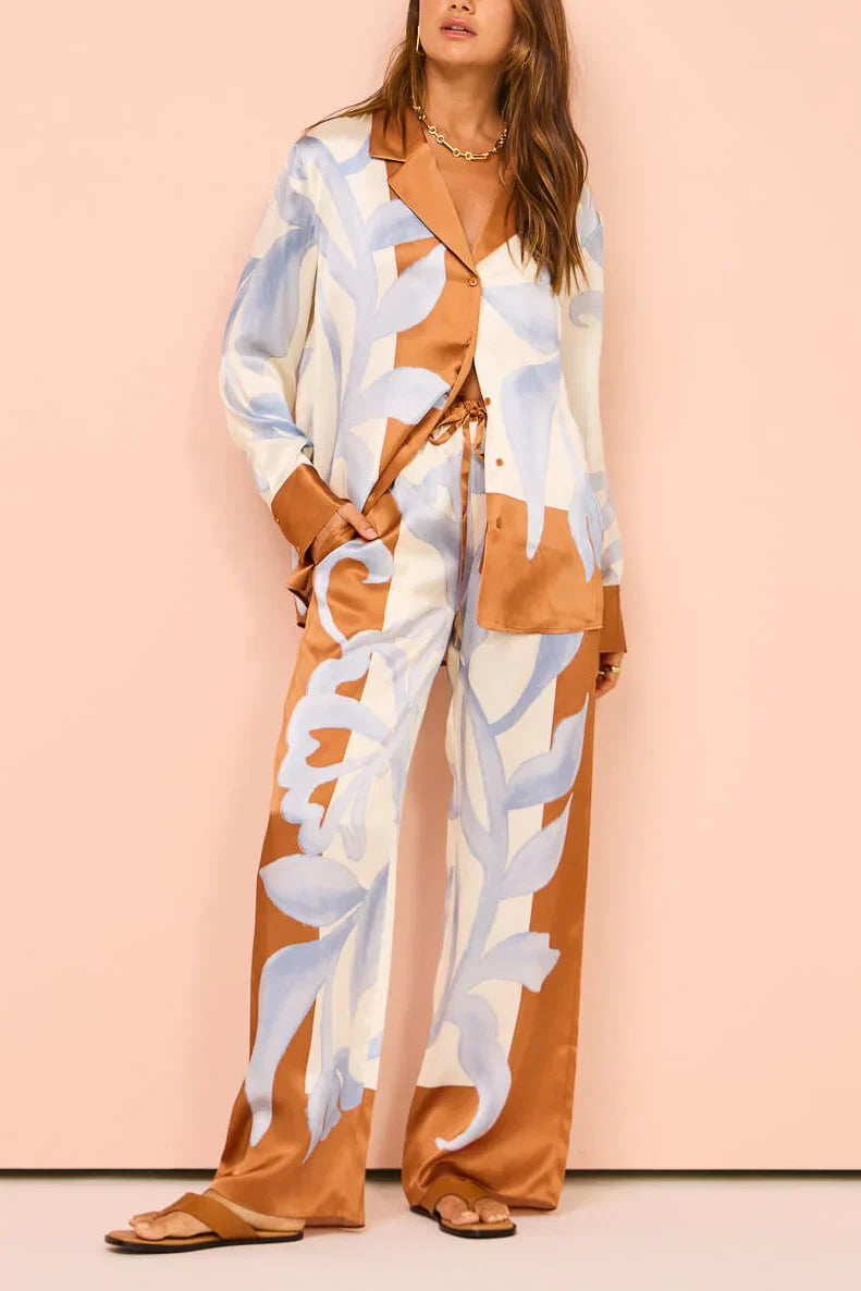 Woman in ivory, brown, and blue floral satin pajama set
