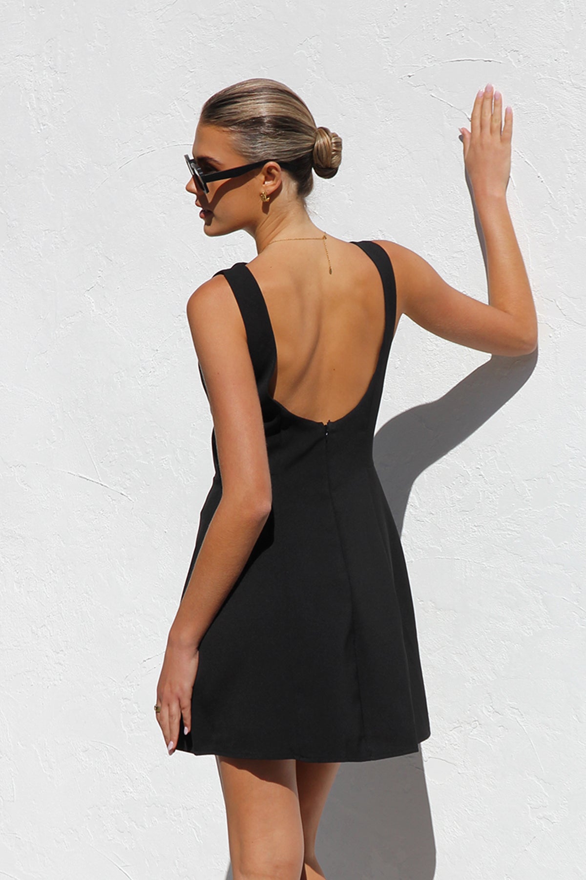 Woman in black sleeveless woven mini dress