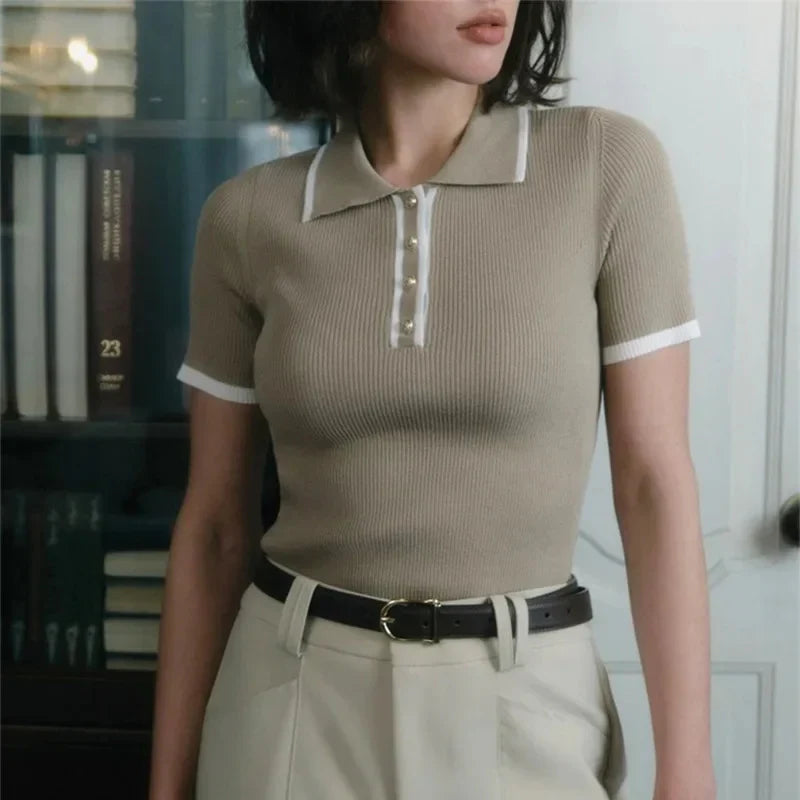 Woman wearing white ribbed knit polo shirt with brown belt and beige trousers