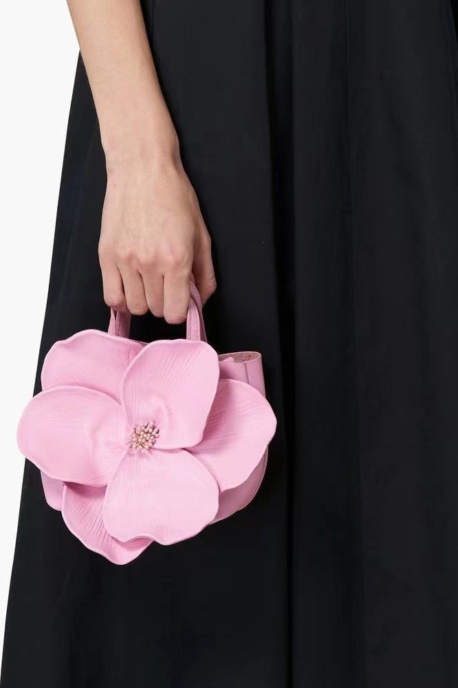 Woman in pink floral chiffon dress holding a red flower-shaped purse