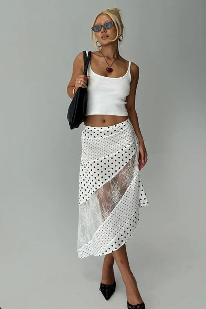 Woman in white tank top and polka dot and lace asymmetrical skirt
