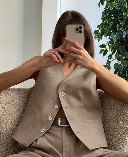Woman in gray wool blend vest and wide leg pants holding a coffee cup and design book.