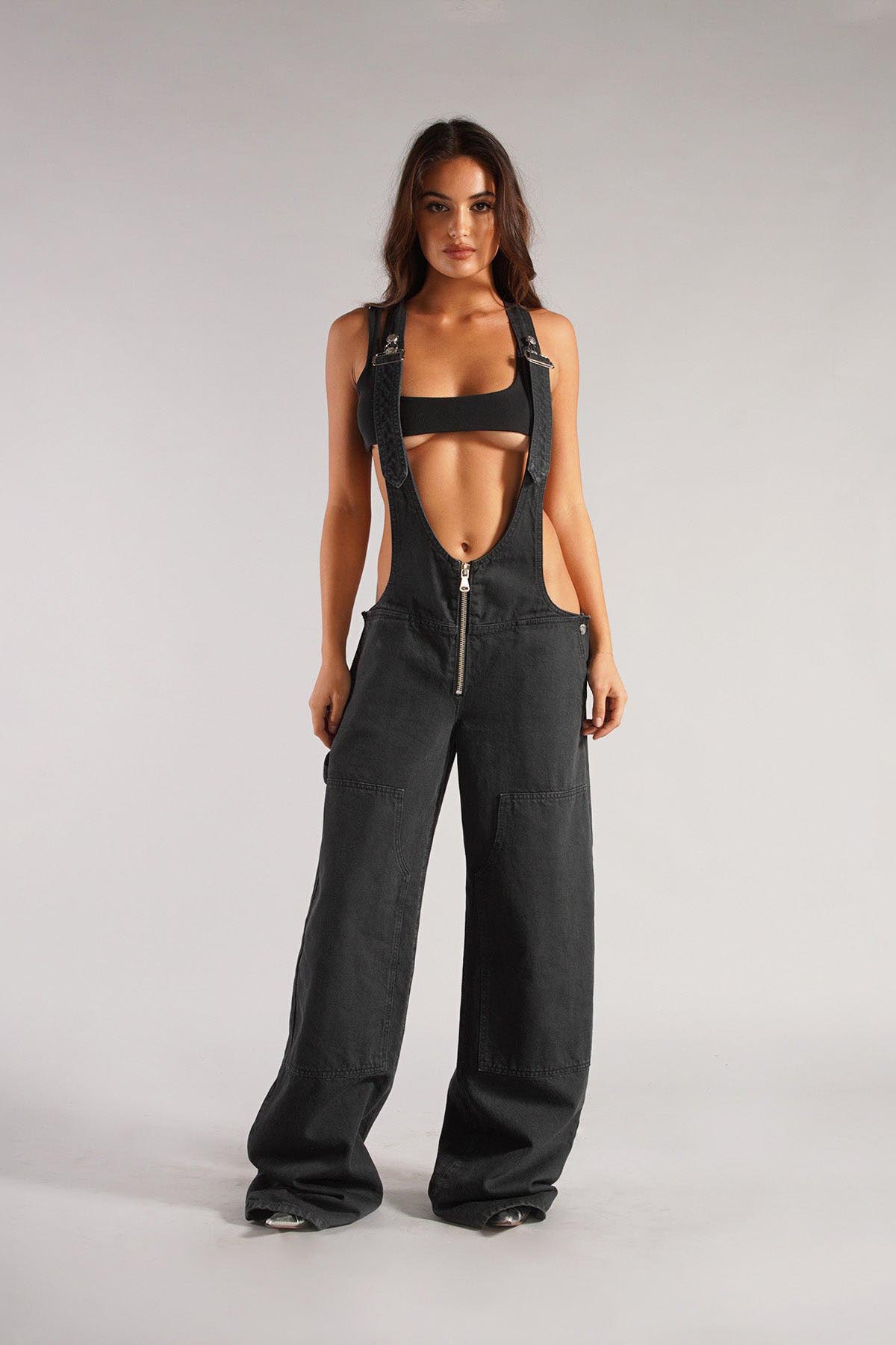 Woman wearing olive green cotton canvas overalls with cutout sides and white crop top