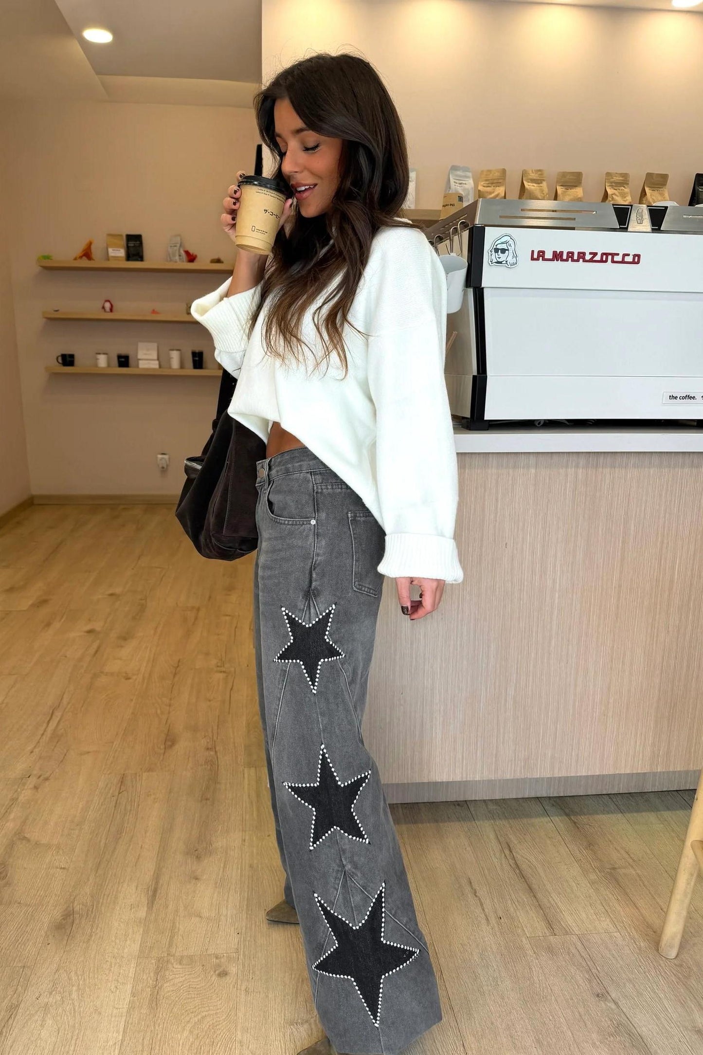 Woman wearing light wash wide leg jeans with star appliqués