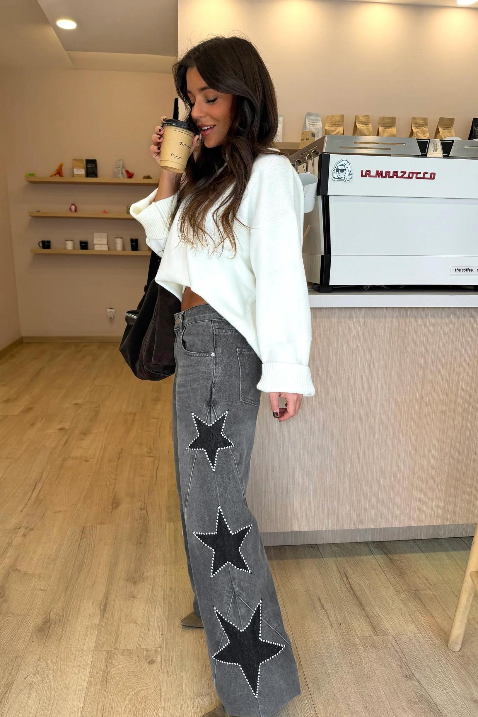 Woman wearing light wash wide leg jeans with star appliqués