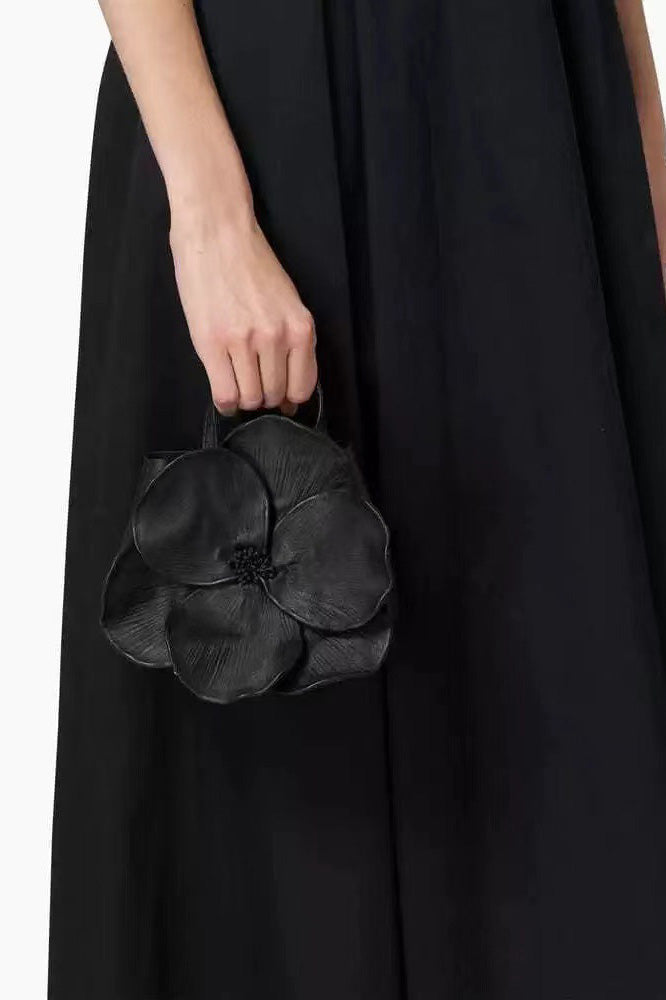 Woman in pink floral chiffon dress holding a red flower-shaped purse