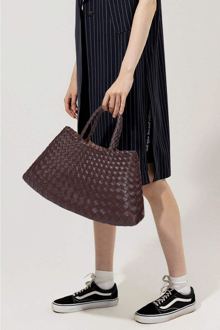 Woman holding brown woven tote bag