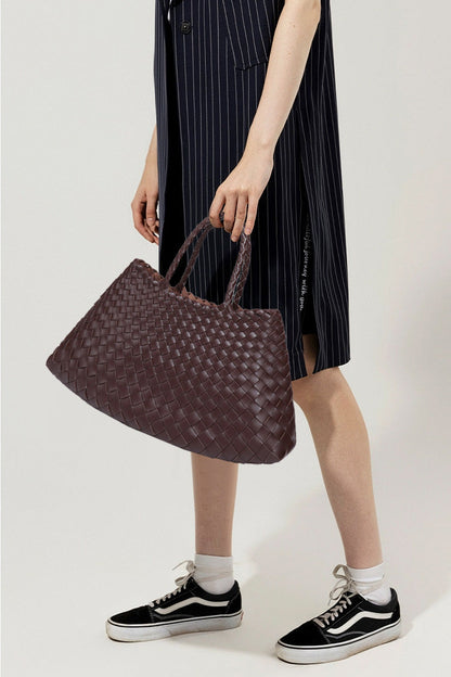 Woman holding brown woven tote bag